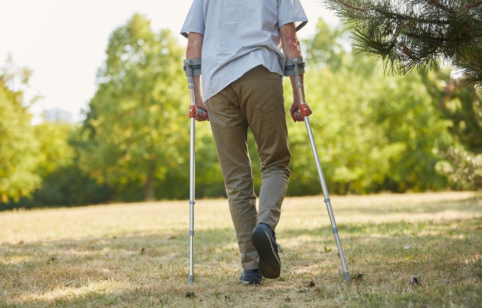 Paciente caminando con muletas durante la recuperación tras una prótesis de cadera o rodilla Paciente caminando con muletas durante la recuperación tras una prótesis de cadera o rodilla
